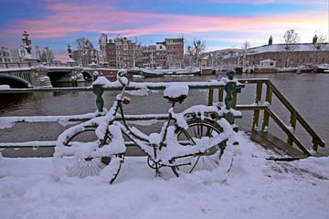Besneeuwd Amsterdam in de winter bij zonsondergang