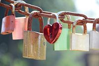 Liefdes hangsloten in verschillende kleuren aan een roestige ketting op een zonnige dag