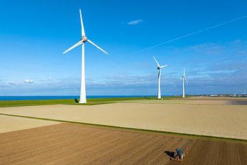 Wind turbines on a levee with a tractor cultivating the soil by Sjoerd van der Wal Photography