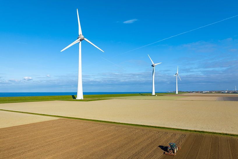 Windturbinen auf einem Deich mit einem Traktor, der den Boden bewirtschaftet von Sjoerd van der Wal Fotografie
