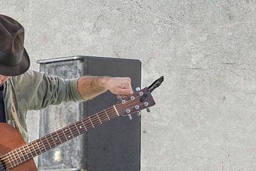Man tunes guitar by Patricia Hofmeester