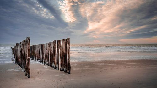 Des poteaux de plage pour un ciel et une mer aux couleurs pastel en soirée