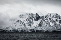 Black and white photo of low-hanging clouds and snow-capped mountains by Martijn Smeets thumbnail