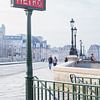 Brug over de Seine met lantaarns en metro bord in Parijs van Angeline Dobber