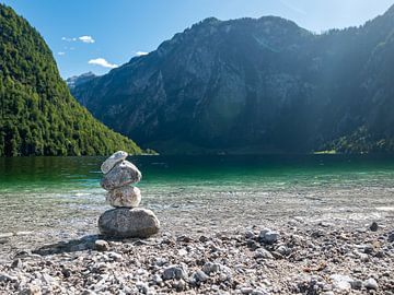 Gestapelde stenen aan het door bergen omringde meer Königssee in Duitsland van Moniek van Rijbroek