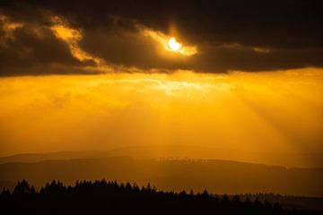 Photo de nuages, au-dessus d'une forêt, avec des rayons de soleil au coucher du soleil sur Fotos by Jan Wehnert