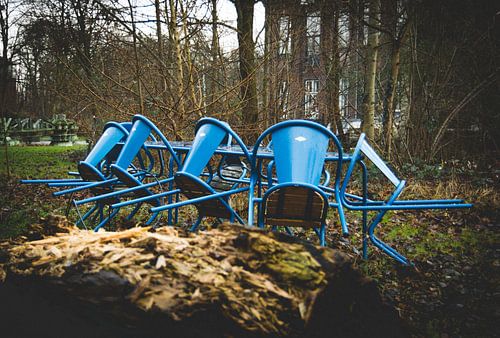 Blauwe stoelen in de regen in een industrieel landschap