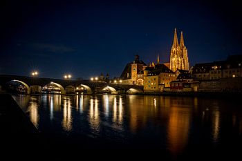View from the Danube on the Regensburg Cathedral and Stone Bridge with lights in Regensburg in the e