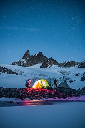 Mountaineers at luminous tent in the mountains