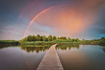 Dreigende wolken en regenboog boven Nederlands landschap