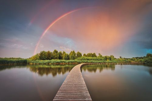 Dreigende wolken en regenboog boven Nederlands landschap