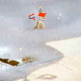 Weerspiegeling in een regenplas van de top van de Utrechtse Domtoren op Koningsdag. sur Margreet van Beusichem