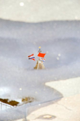 Weerspiegeling in een regenplas van de top van de Utrechtse Domtoren op Koningsdag.