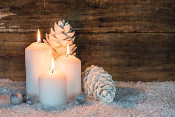 Advent en Kerstmis kaarsvlammen met witte en zilveren decoratie, sneeuw en houten achtergrond van Alex Winter