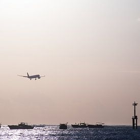 Landend vliegtuig boven zee tijdens zonsondergang von Chantal Schutte
