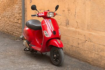 Scooter Vespa rouge dans une vieille rue en France