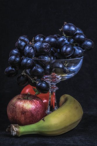 druiven in een glas met voet en ander fruit daaronder
