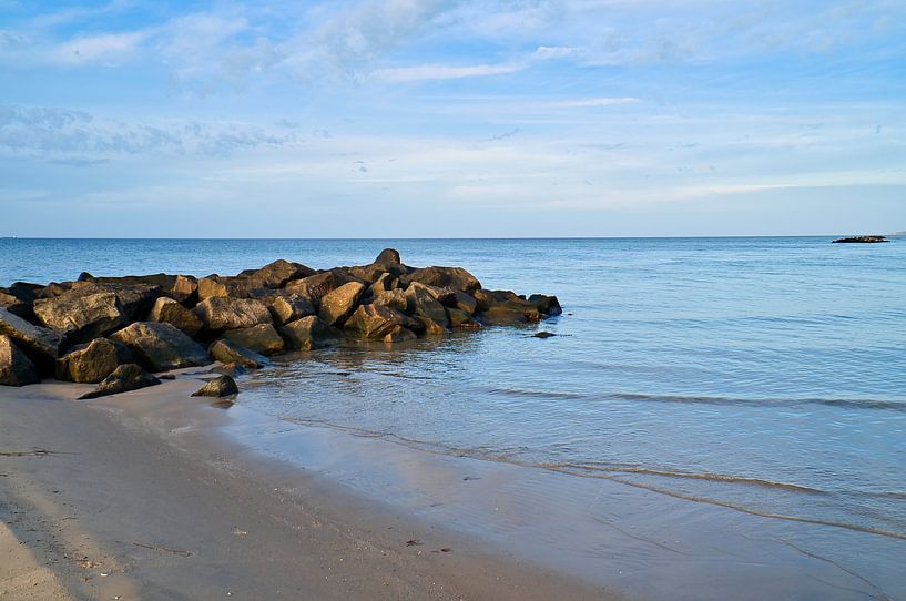 Stenen rotsblok steekt in zee op een zandstrand in Denemarken van Martin Köbsch