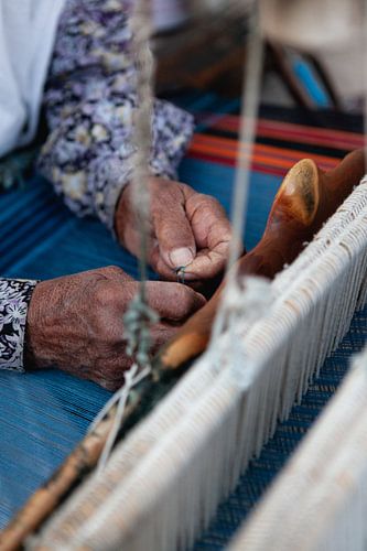 Oude handen van een weefster