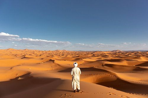 African man looks out over the dunes of the African desert, the Sahara