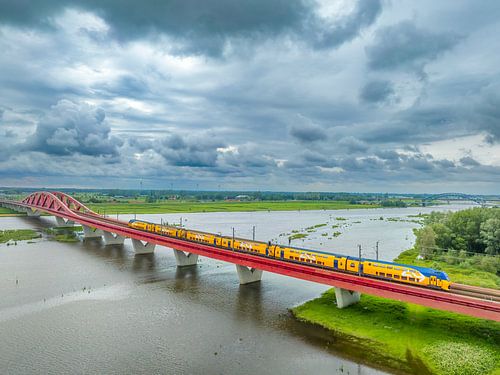 Hanzeboog spoorbrug over de IJssel met donkere wolken