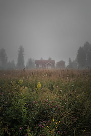 Morning mist in the Swedish wilderness – Vertical photo print of a red log cabin in Värmland by Dylan Winter Visuals