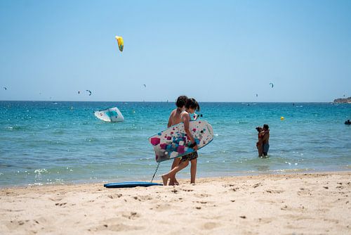 Bodysurfers (kinderen) lopend langs het strand van Tarifa.