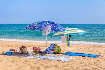 Twee parasols en strandspullen aan zee