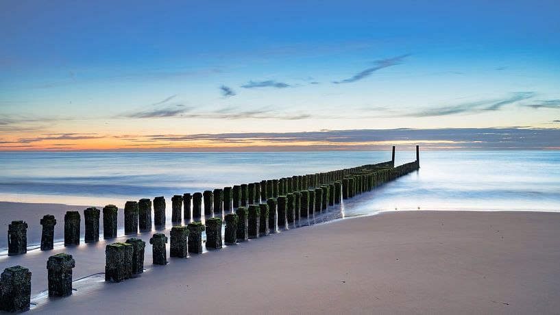 Wellenbrecher aus Holzpfählen bei Sonnenuntergang über der Nordsee von Fotografiecor .nl