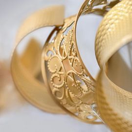 gold colored ornate bracelet in a white environment by Tony Vingerhoets