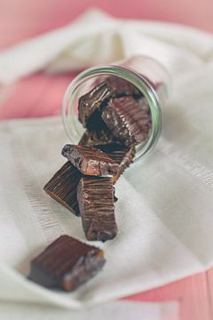 Des bonbons au caramel faits maison et enrobés de chocolat tombent d'un verre