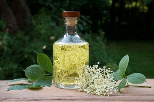Zelfgemaakte vlierbloesemdrank met suiker en citroen in een glazen fles op een houten tafel in de tu