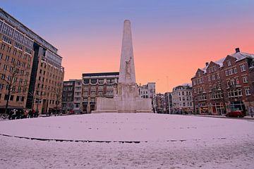 Besneeuwde Dam plein met het nationaal monument bij zonsondergang in Amsterdam Nederland van Eye on You