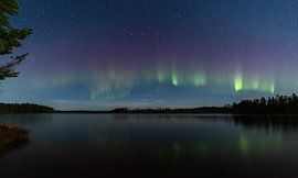 Magical aurora borealis over a calm lake in Sweden by Fototante