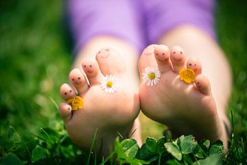 Little girl's toes decorated with daisies and buttercups and with drawn-on smiley faces by BeeldigBeeld Food & Lifestyle