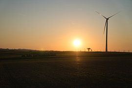 Windturbine bij zonsondergang op een weiland van Martin Köbsch