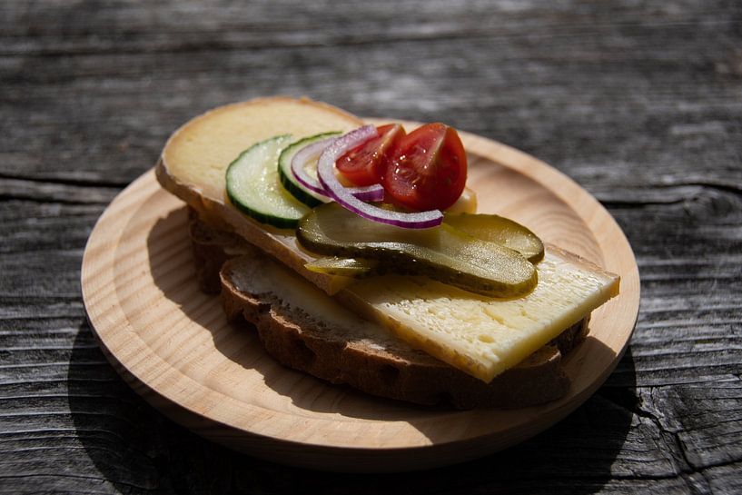 Delicious cheese sandwich with gherkins onions and tomatoes on a wooden plate by David Esser