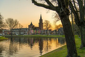 Coucher de soleil sur le canal de la ville de Leeuwarder et le clocher de l'église Dominicus sur Harrie Muis