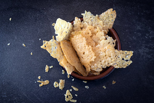 knusprige Parmesan-Chips, hausgemachter Party-Snack in einer Schale auf dunklem Schiefer-Hintergrund