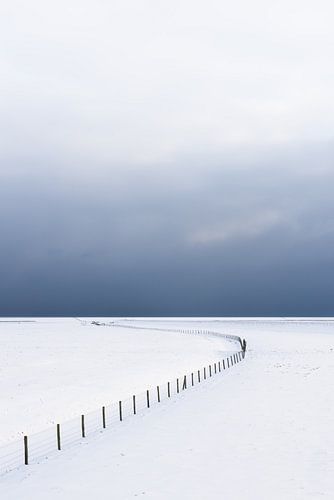 Een leeg winters landschap bedekt met sneeuw in het Nationaal park Lauwersmeer. Aan de horizon drijv