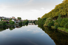 Ruhiger Fluss mit Baumspiegelungen und einer alten Brücke in Südfrankreich von Fechita Florentina Catalina