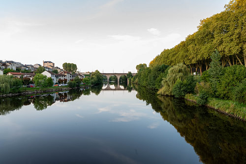 Calm river with tree reflections and old bridge in southern France
