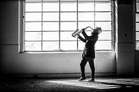 Dark man playing saxophone in an industrial environment