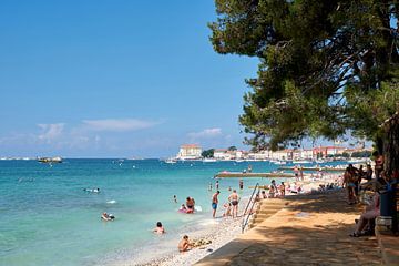 Strand mit Urlaubern an der Küste der historischen Hafenstadt Porec an der Adria in Kroatien