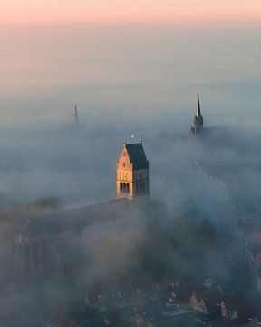 Churches of Bolsward above the fog at sunrise by Ewold Kooistra