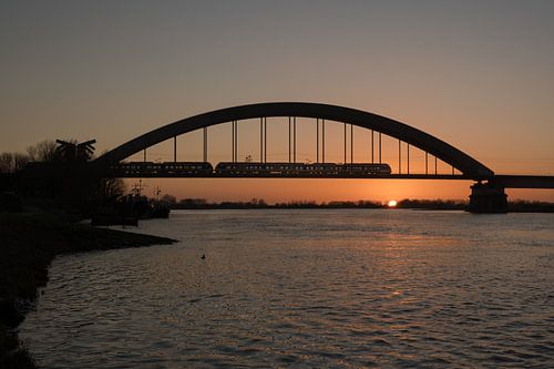 Trein over spoorbrug Culemborg bij zonsondergang