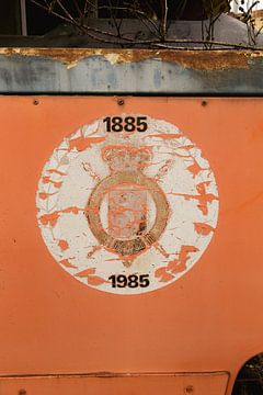 Vergeten Geschiedenis: Verwaarloosde Tram met Vervallen Logo, 1885-1985, Tegen Oranje Achtergrond van Melvin Meijer