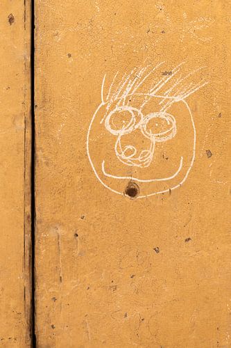 Visage dessiné sur un mur ocre dans le sud de la France