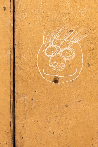 Gezeichnetes Gesicht auf einer ockerfarbenen Wand in Südfrankreich von Cindy Mulder