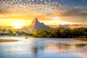 La baie de Tamarin sur l'île Maurice au coucher du soleil avec une chaîne de montagnes et des pagaye